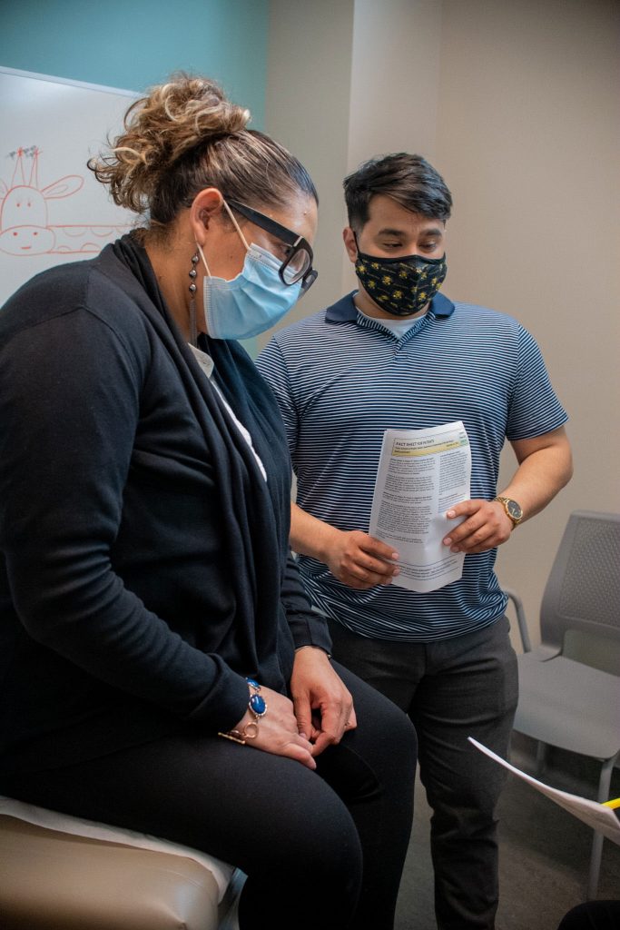 A woman sits in a doctor's office with an interpreter by her side.